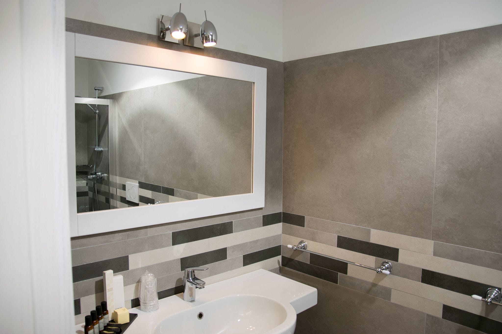 A modern bathroom with a large mirror, a sink, and a shower.