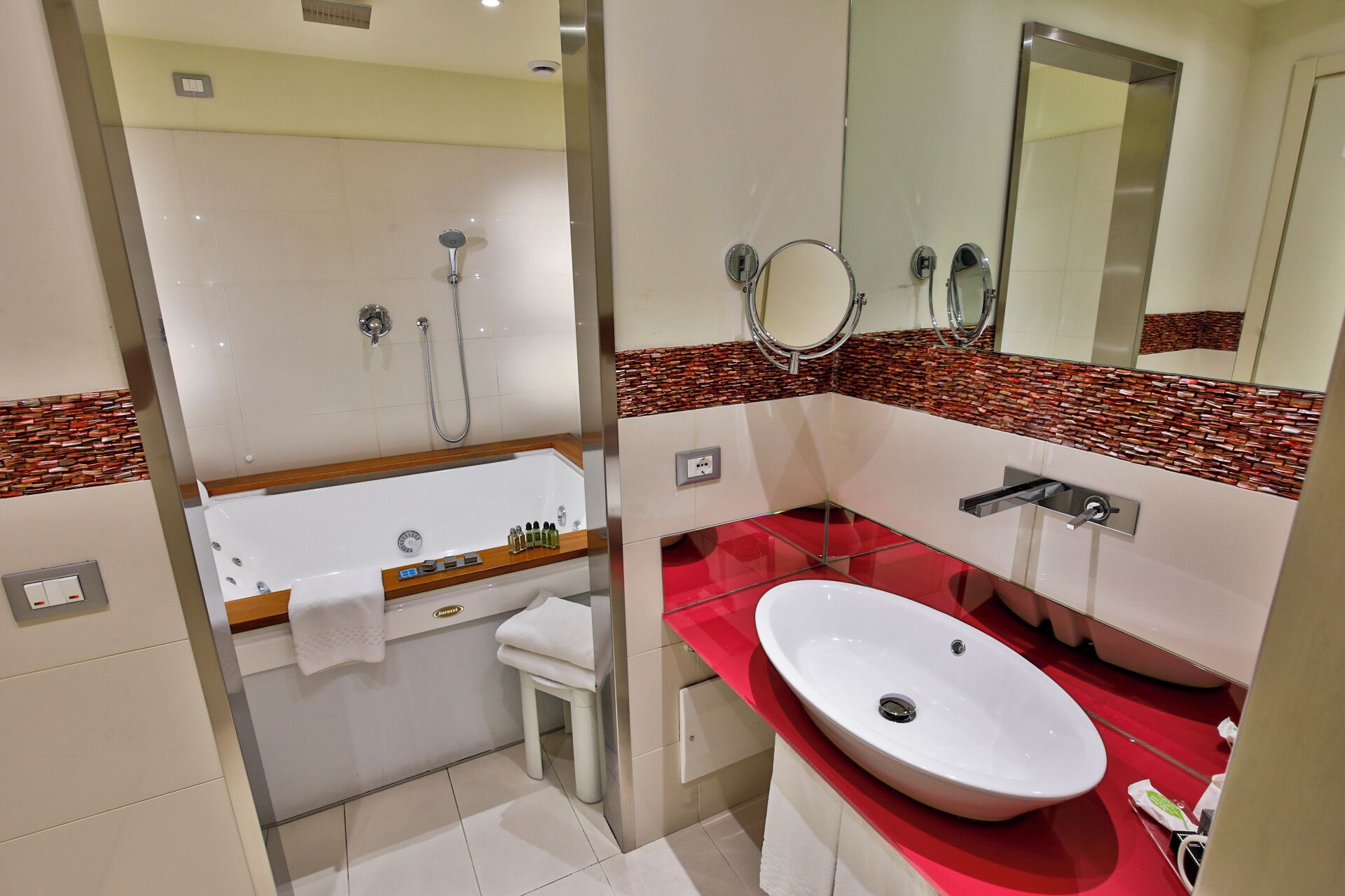 Une salle de bain moderne avec une baignoire, un lavabo rouge et un miroir.