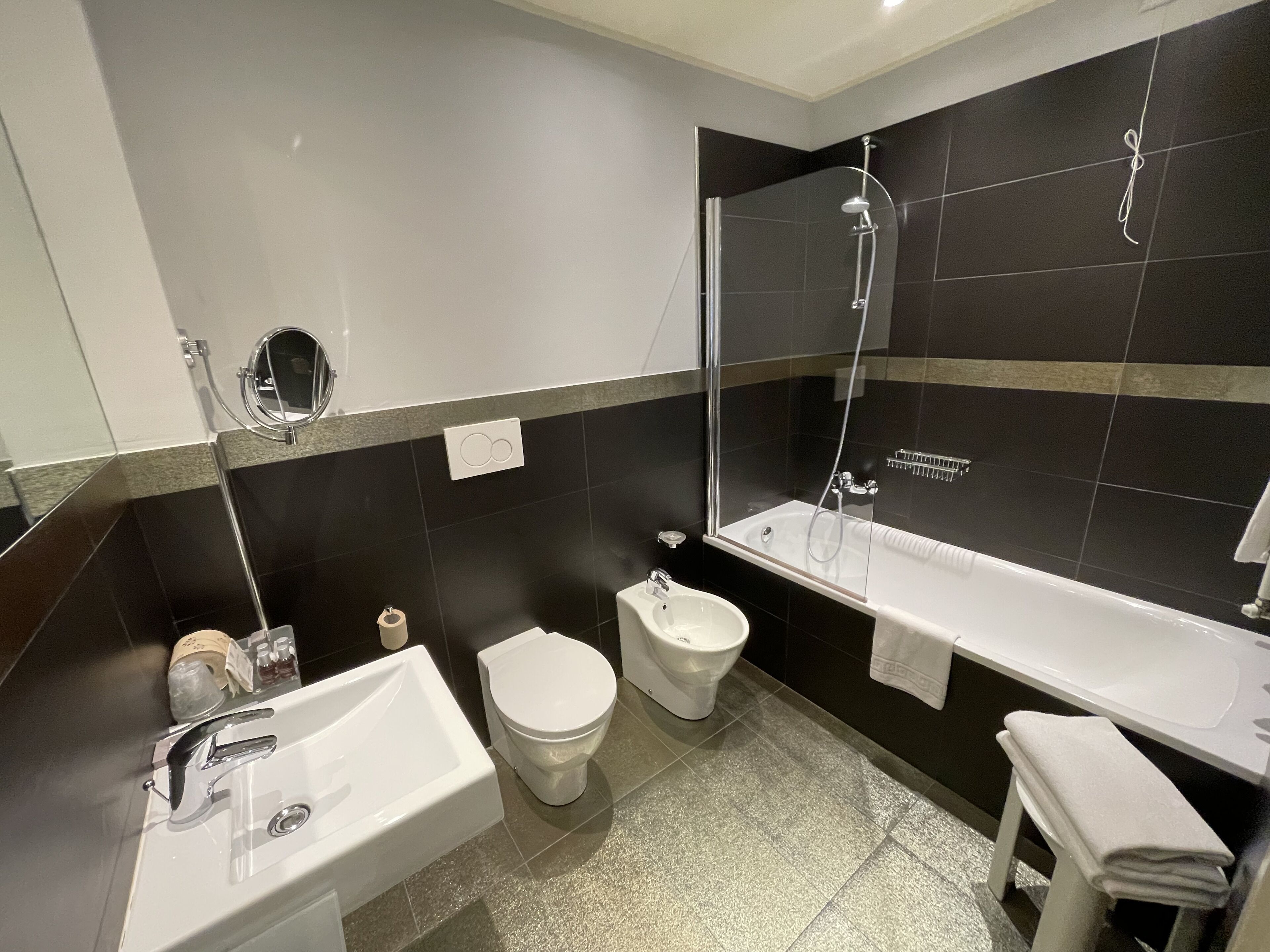 Un baño moderno con lavamanos, inodoro, bidé y zona de ducha con mampara de vidrio.