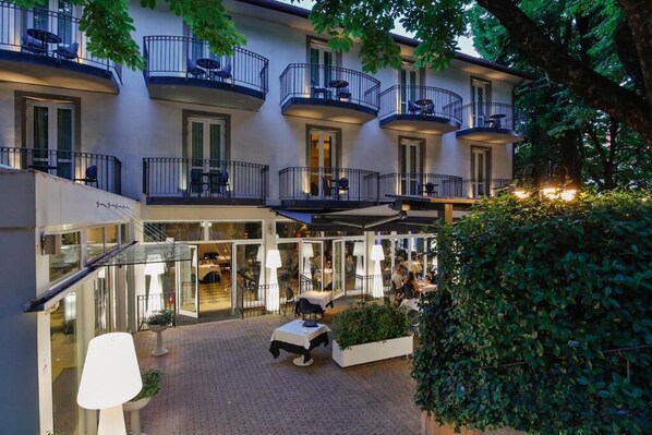A multi-story hotel with outdoor seating areas, balconies, and a central courtyard. - Boutique Hotel Calzavecchio (Casalecchio di Reno)