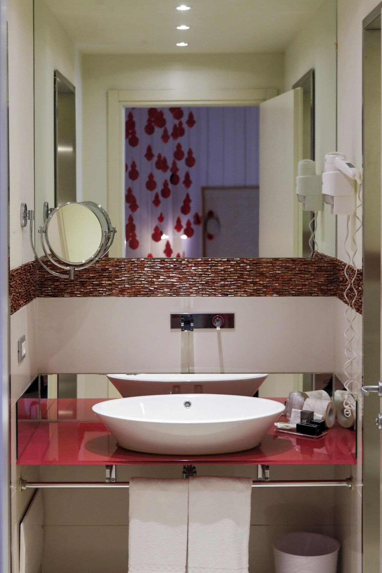 Ein modernes Badezimmer mit einem großen Spiegel, einem runden Waschbecken und einer roten Arbeitsplatte.