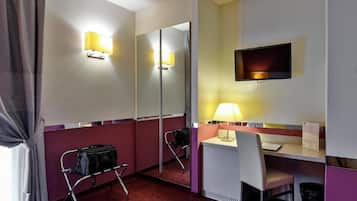 Ein Hotelzimmer mit Schreibtisch, Stuhl, Spiegel und einem an der Wand befestigten Fernseher.