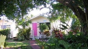 A house with a pink door, surrounded by lush greenery and a paved pathway. - Silver Sands Villas (Fort Myers Beach)
