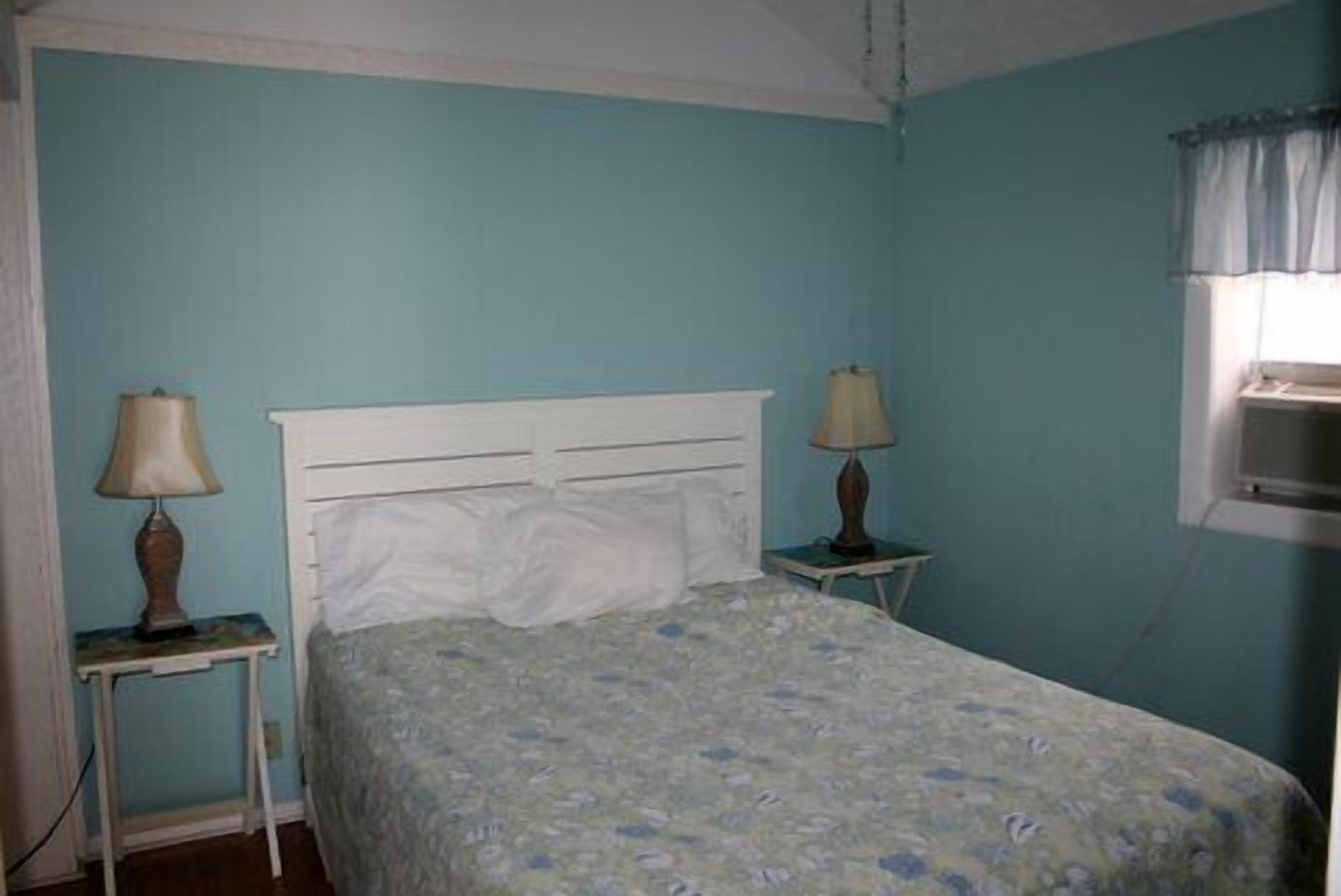 A bedroom with a single bed, two bedside tables, and a window with a curtain.