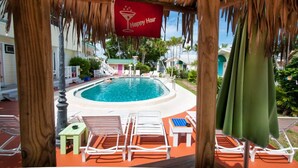 A pool area with lounge chairs and a 'Happy Hour' sign. - Silver Sands Villas (Fort Myers Beach)