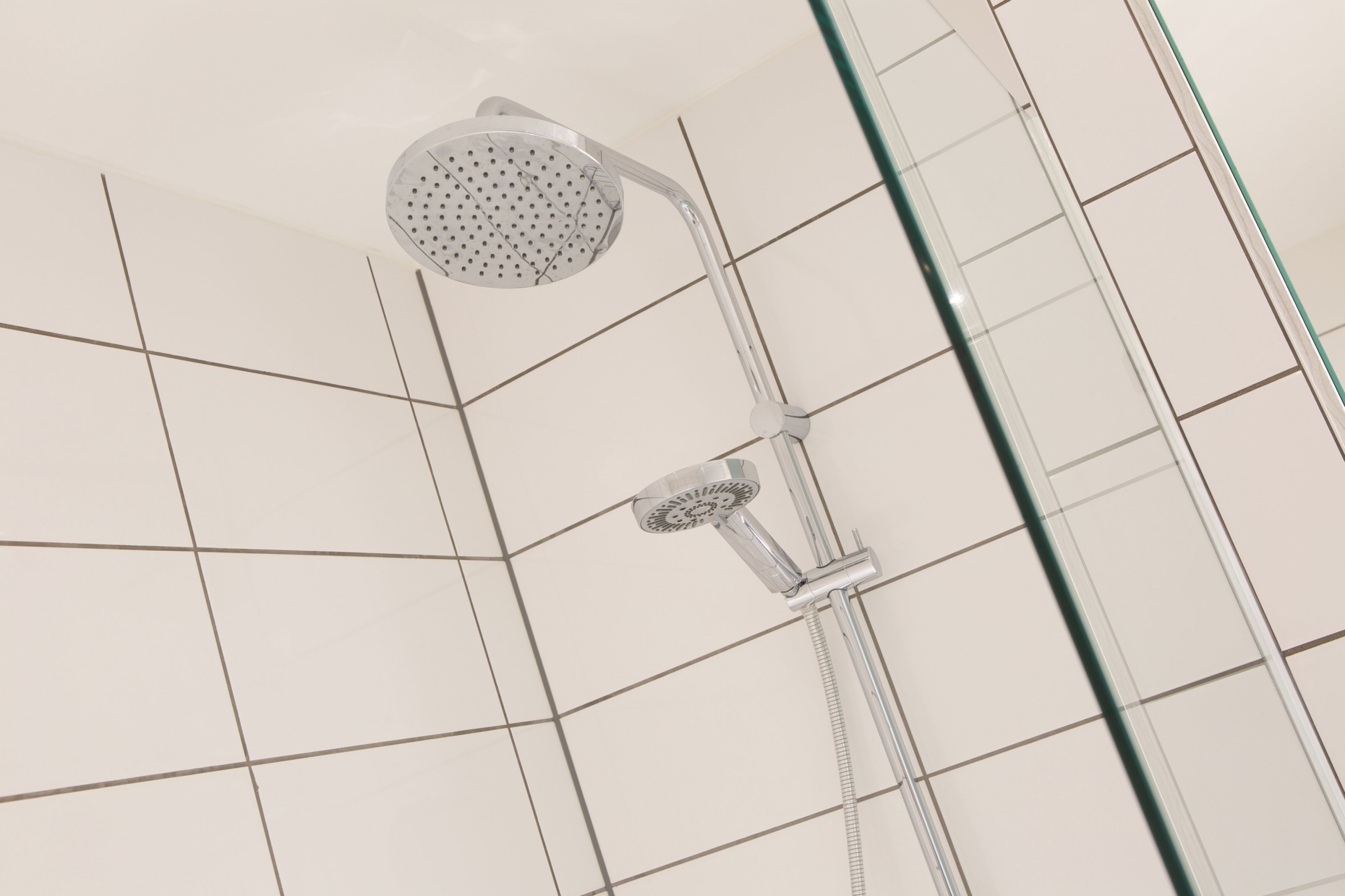 A shower with a handheld showerhead and a wall-mounted faucet.