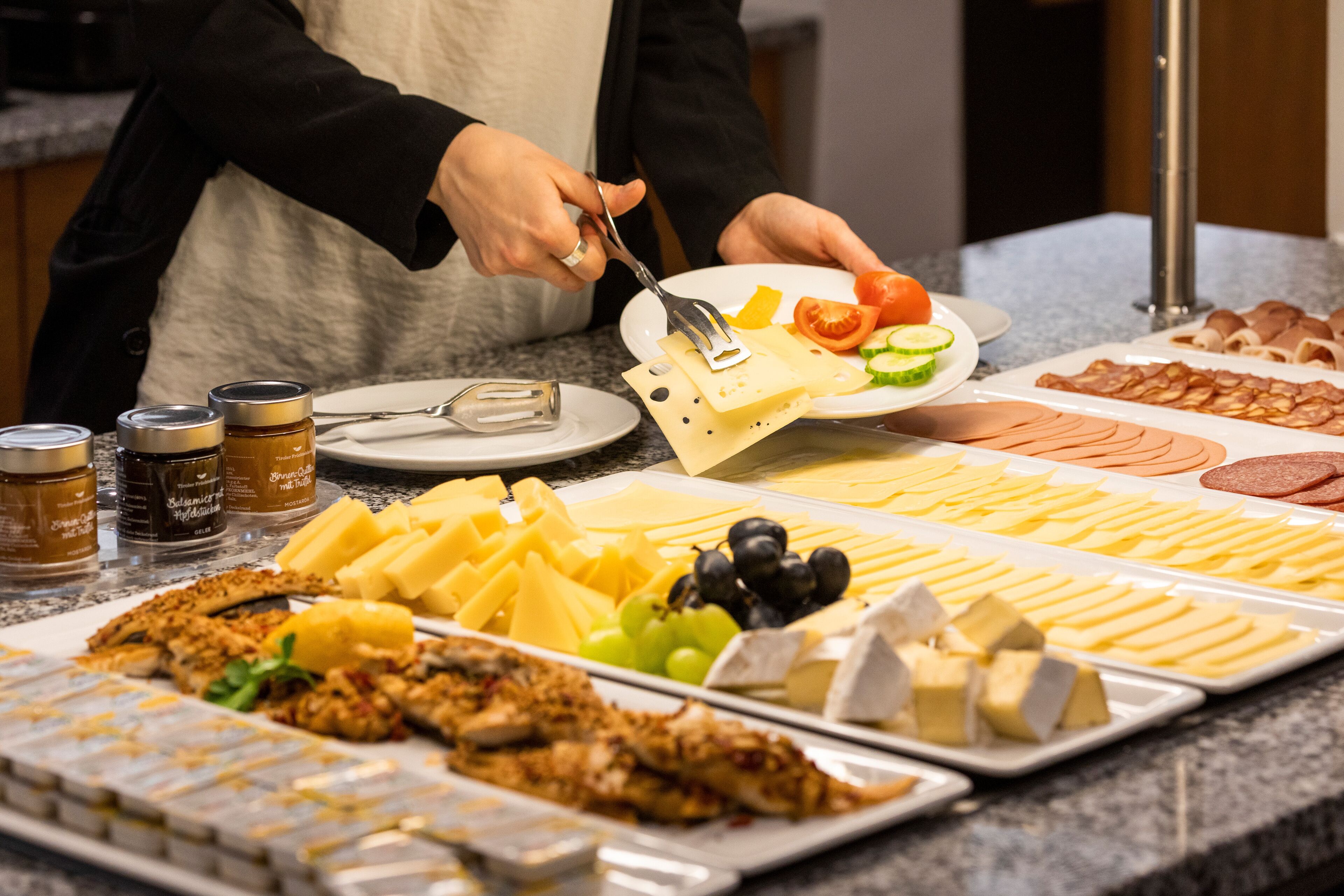 Een buffet met verschillende soorten eten, waaronder kaas, vlees en fruit.