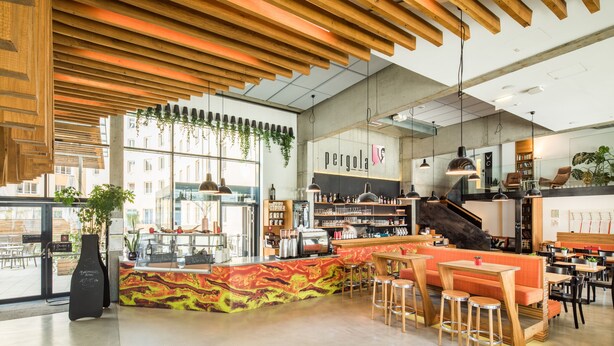 Un café moderno con techo de madera, zona de bar y diferentes disposiciones de asientos.
