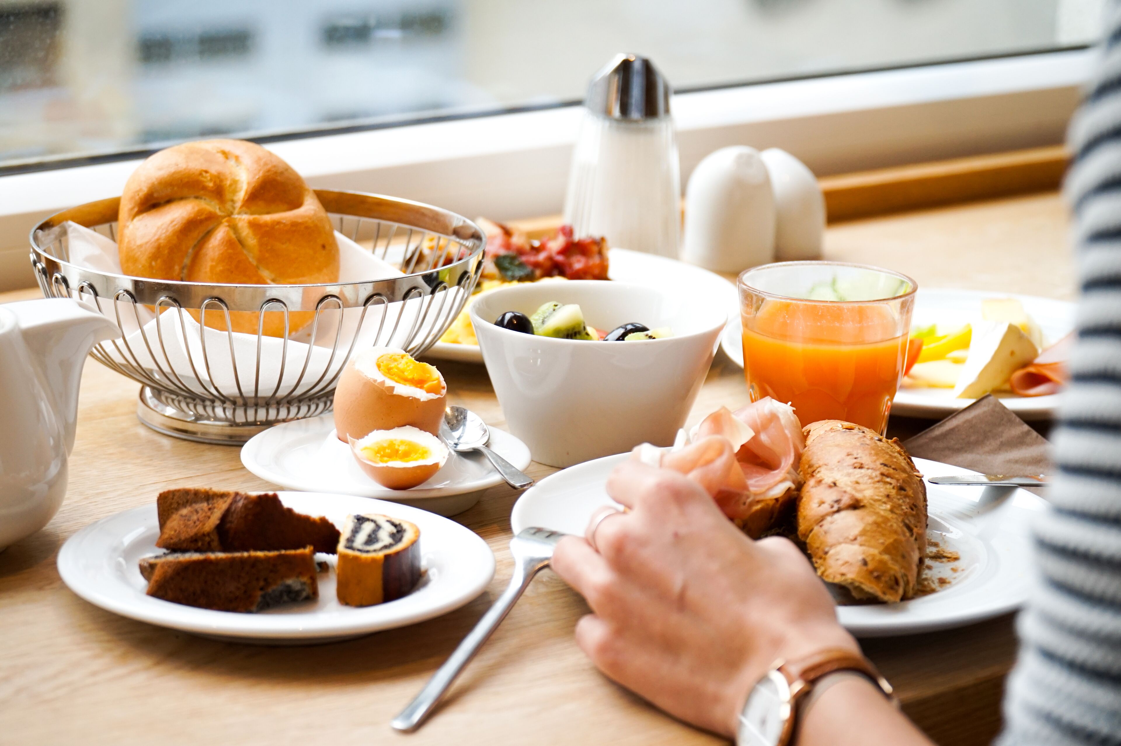Una mesa de desayuno con pan, huevos, fruta y jugo.