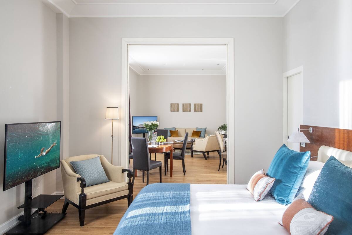 Ein Hotelzimmer mit Bett, Fernseher, Essbereich und Blick auf den Essbereich.