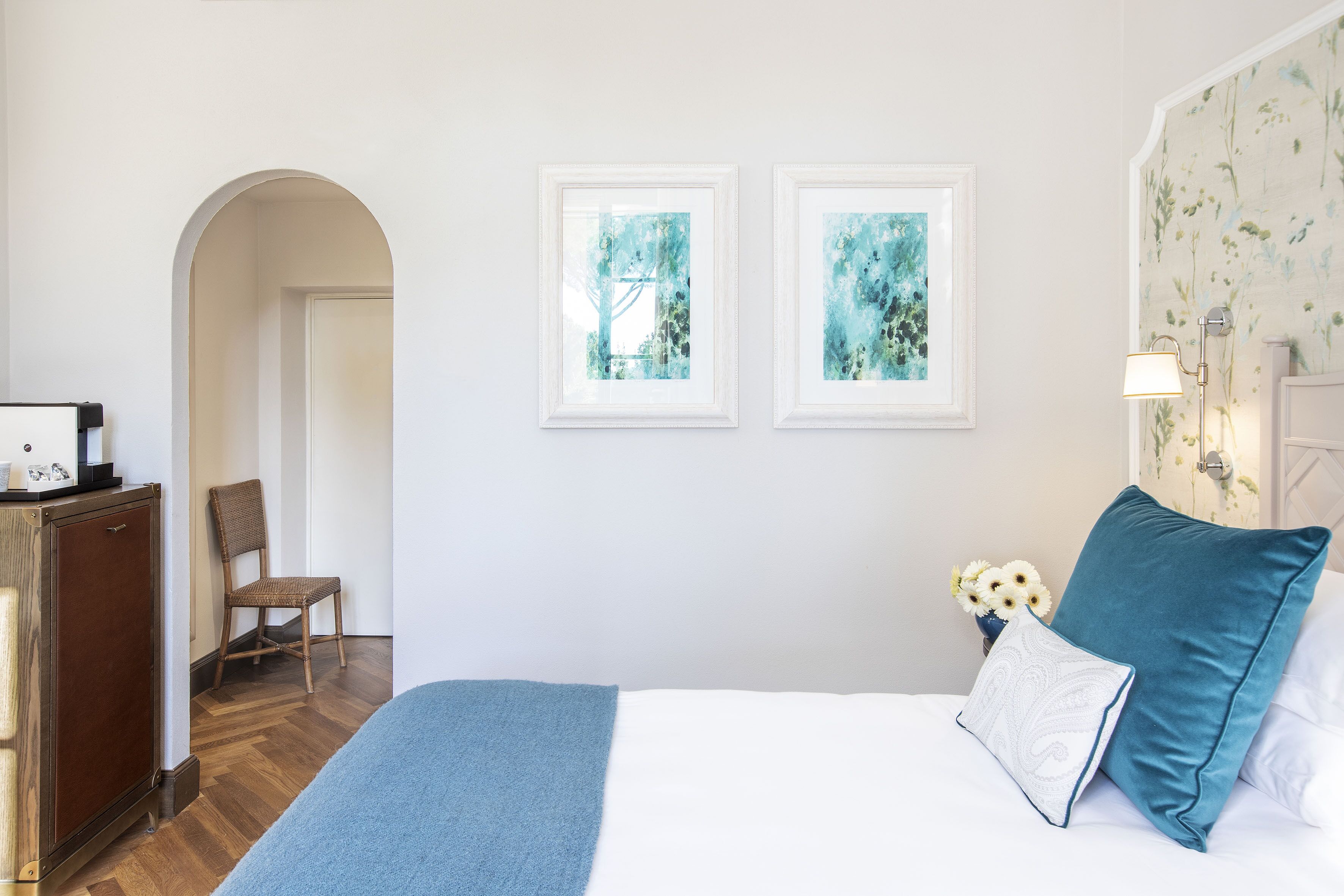 Una camera da letto con un letto, una cassettiera, una sedia e due quadri appesi al muro.