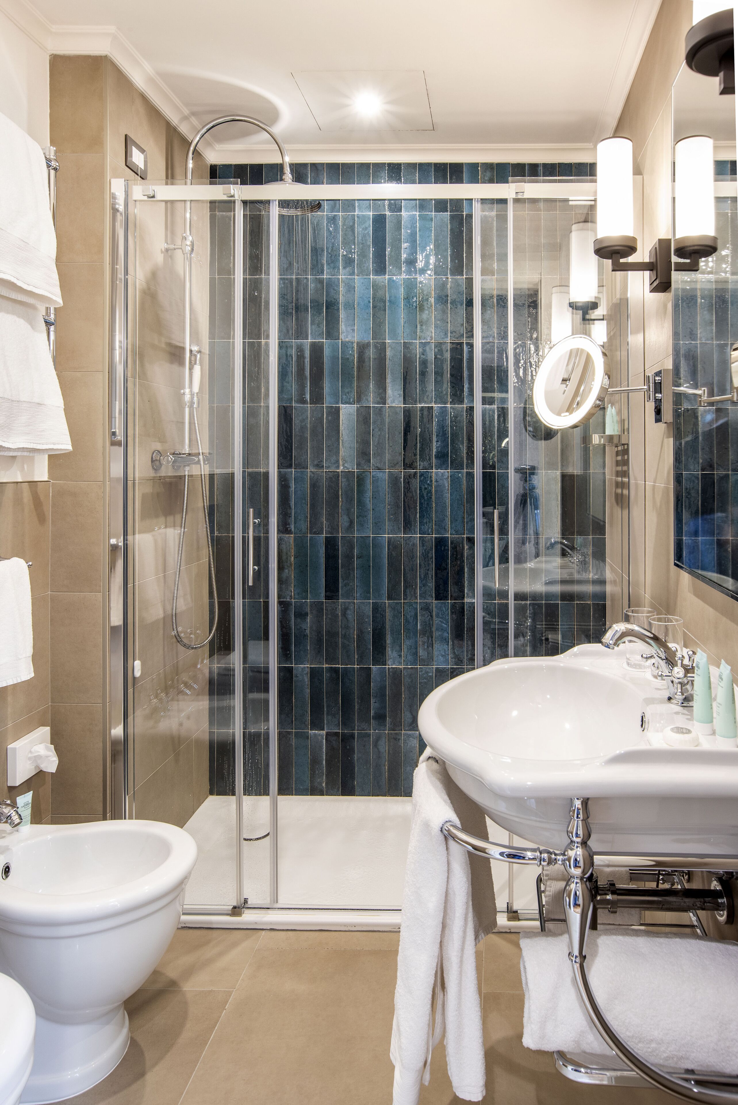 Et moderne badeværelse med et glasafskærmet brusebad, en hvid vask og en bidet.