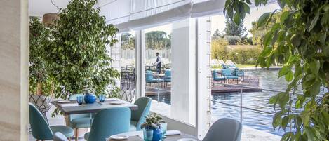 Un comedor interior con vistas a un cuerpo de agua y vegetación.
