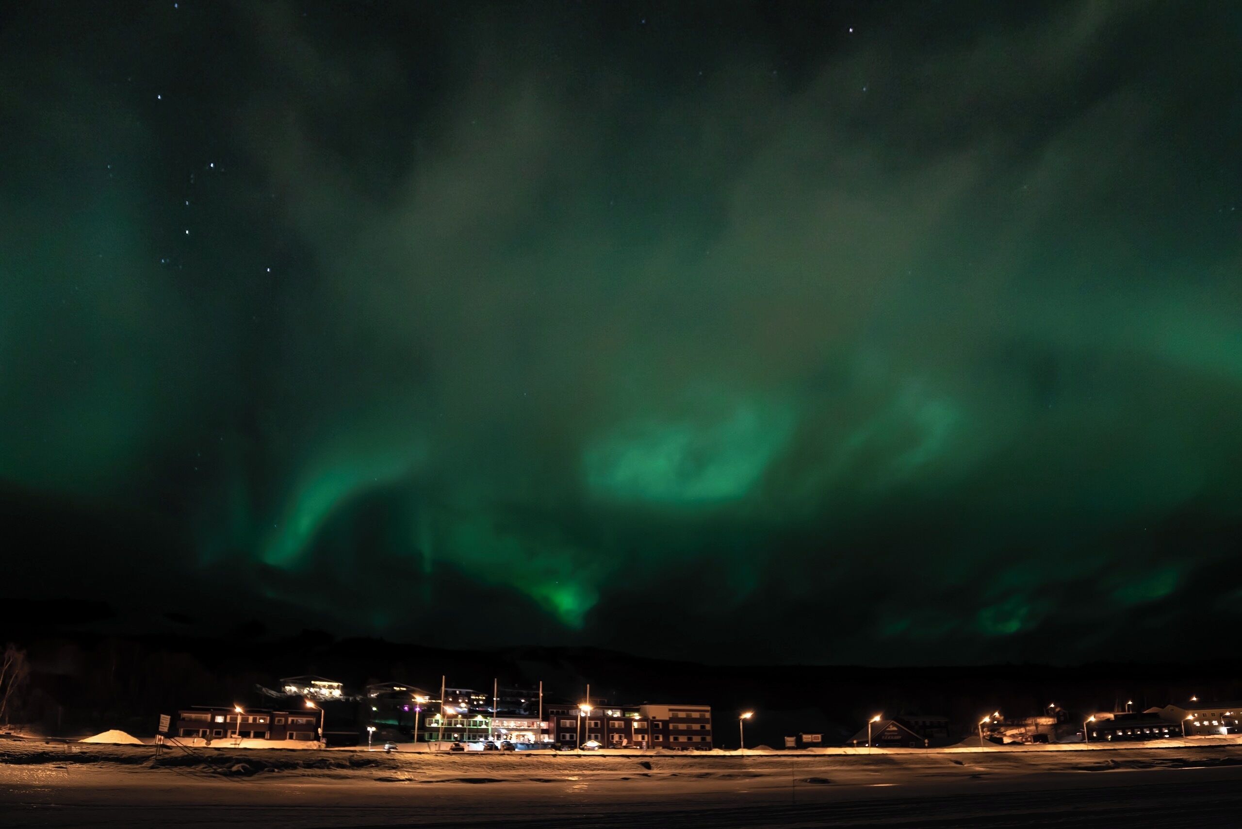 A nighttime view of a building with a parking lot and a road in the foreground.