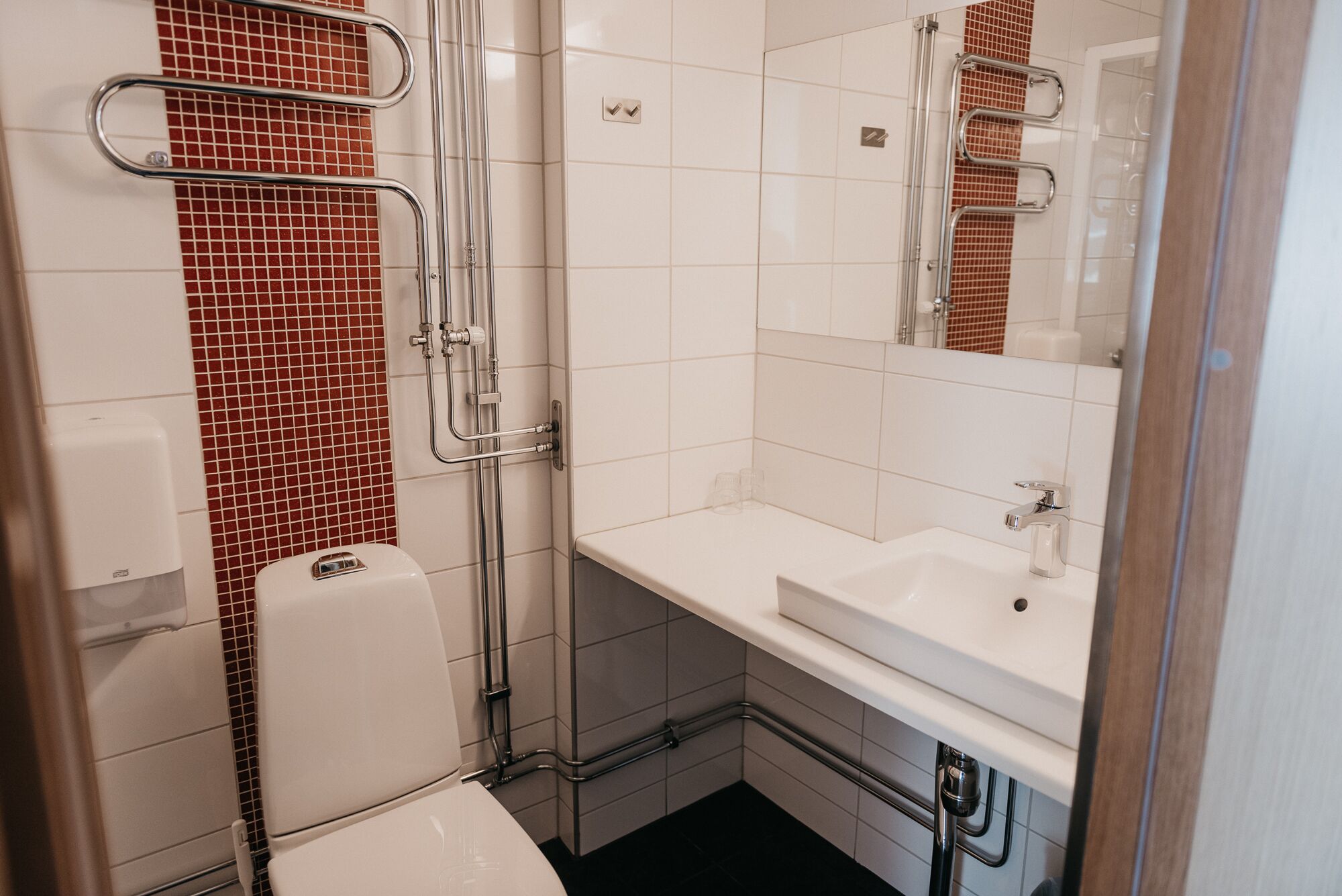 A modern bathroom with a white sink, a mirror, and a toilet.