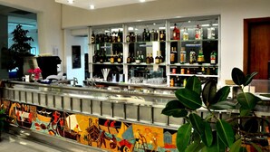 A bar area with shelves of liquor bottles, a decorative tiled backsplash, and a potted plant. - Riviera Spineta (Battipaglia)