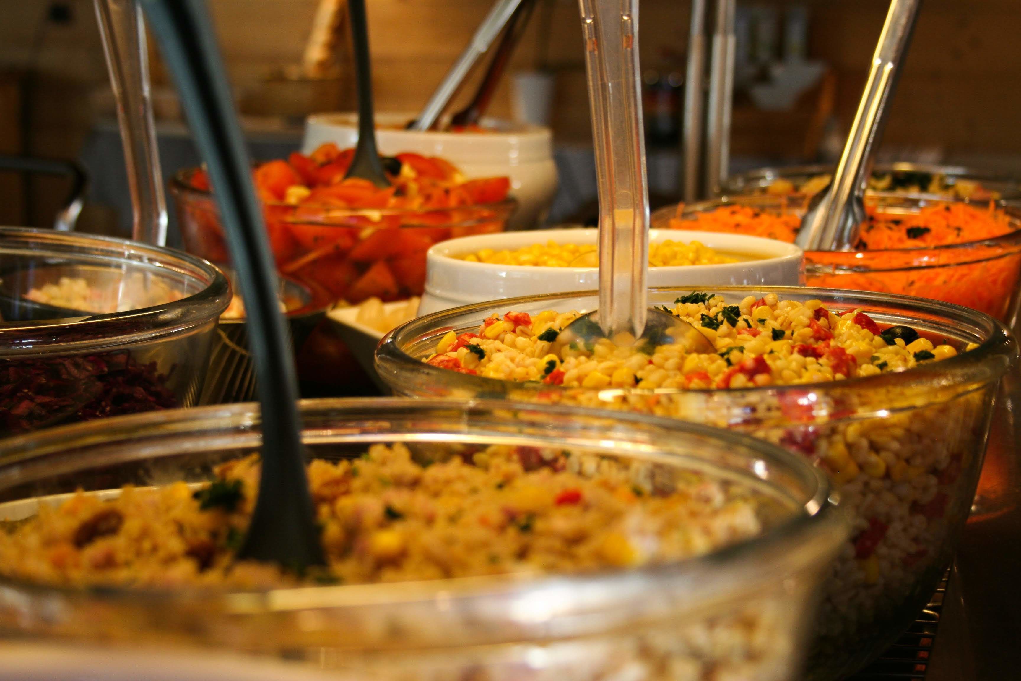 Un bufé con diversas opciones de comida, como ensaladas y granos.