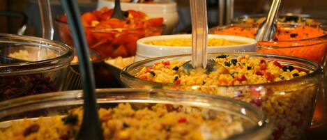 Un bufé con diversas opciones de comida, como ensaladas y granos.
