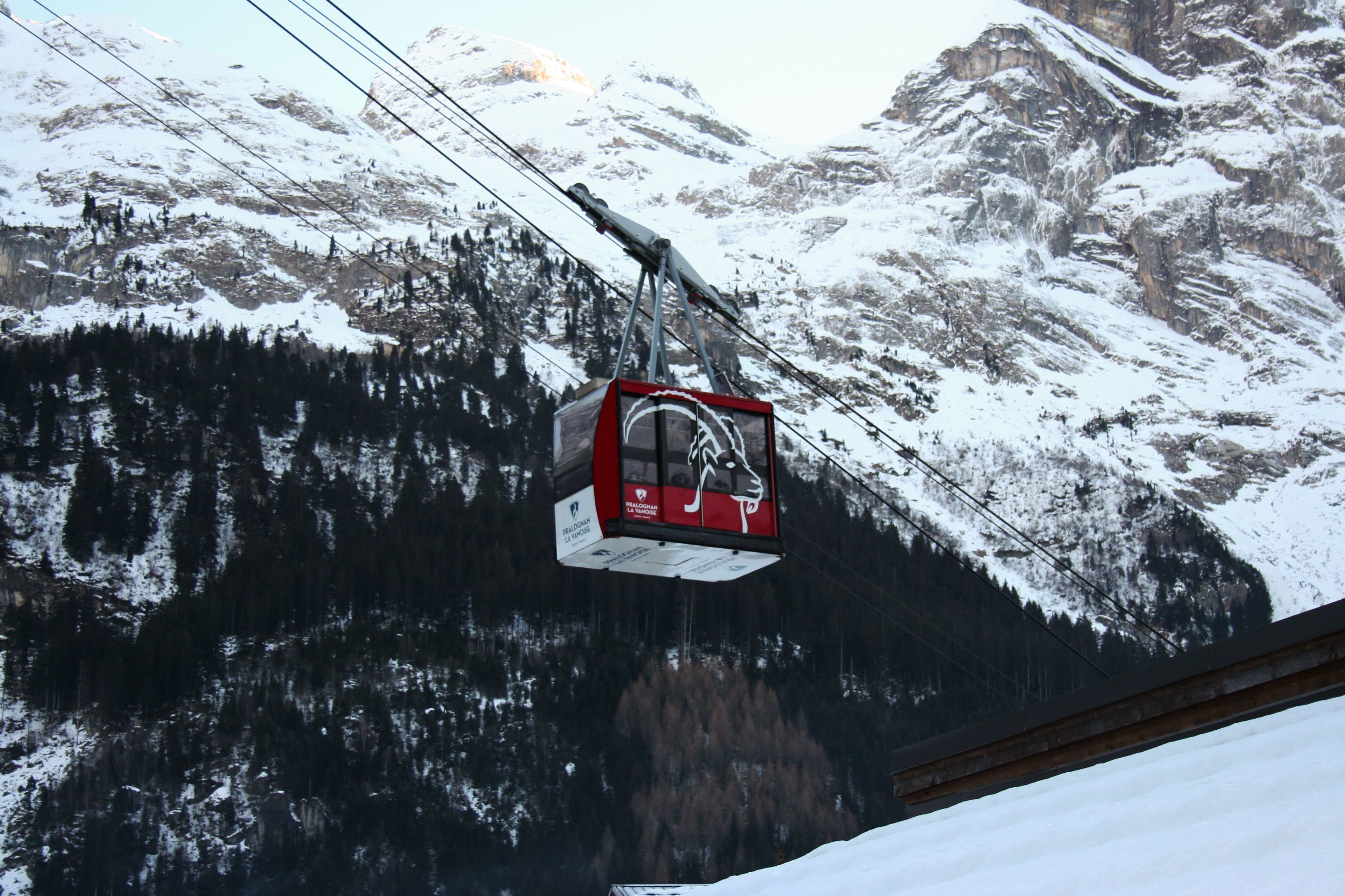 A cable car suspended over a snowy mountain landscape.
