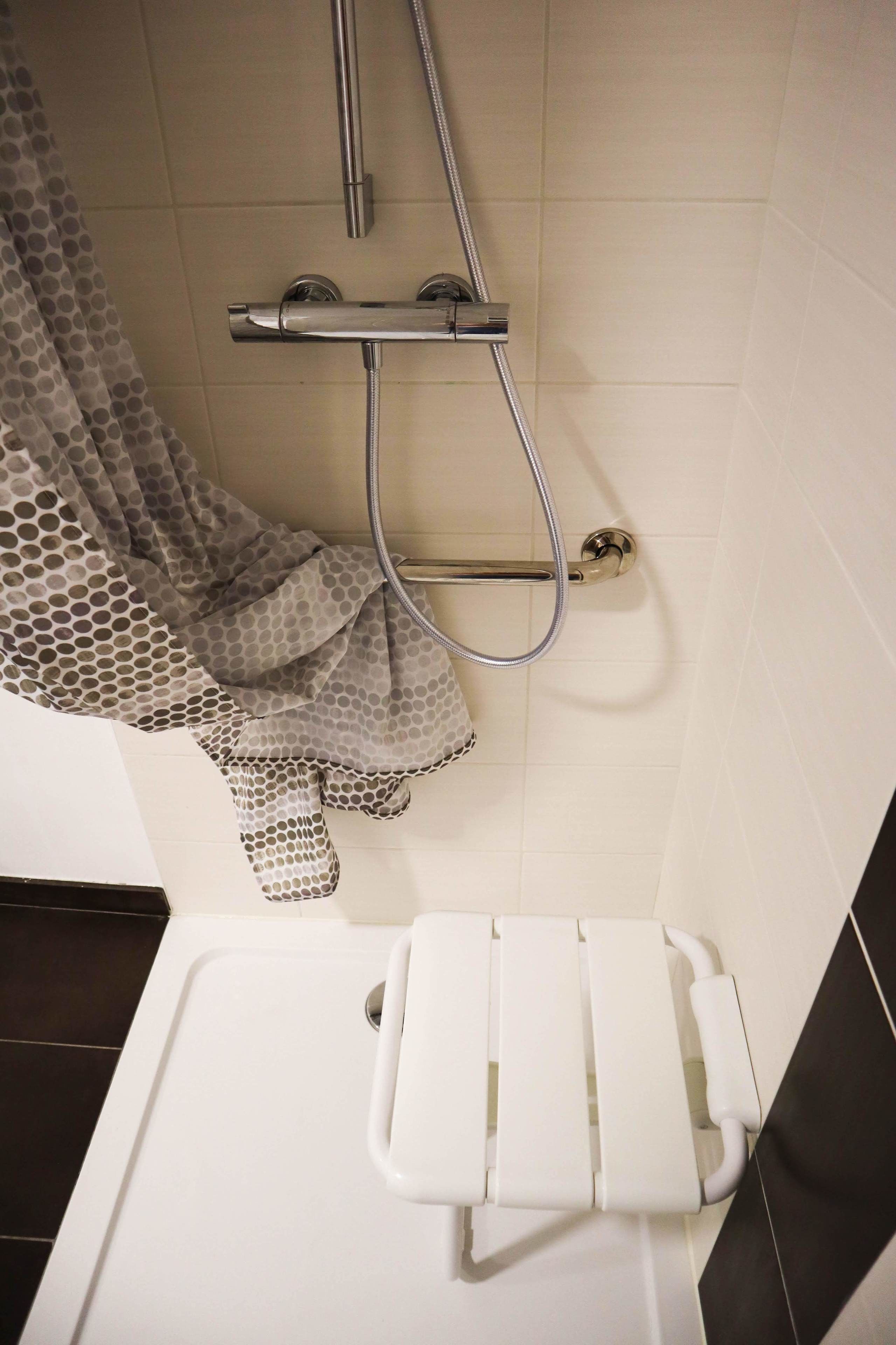 A bathroom with a shower, a toilet, and a towel rack.