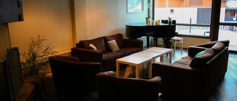A cozy living room with a brown leather sofa, a wooden coffee table, and a TV on a stand.
