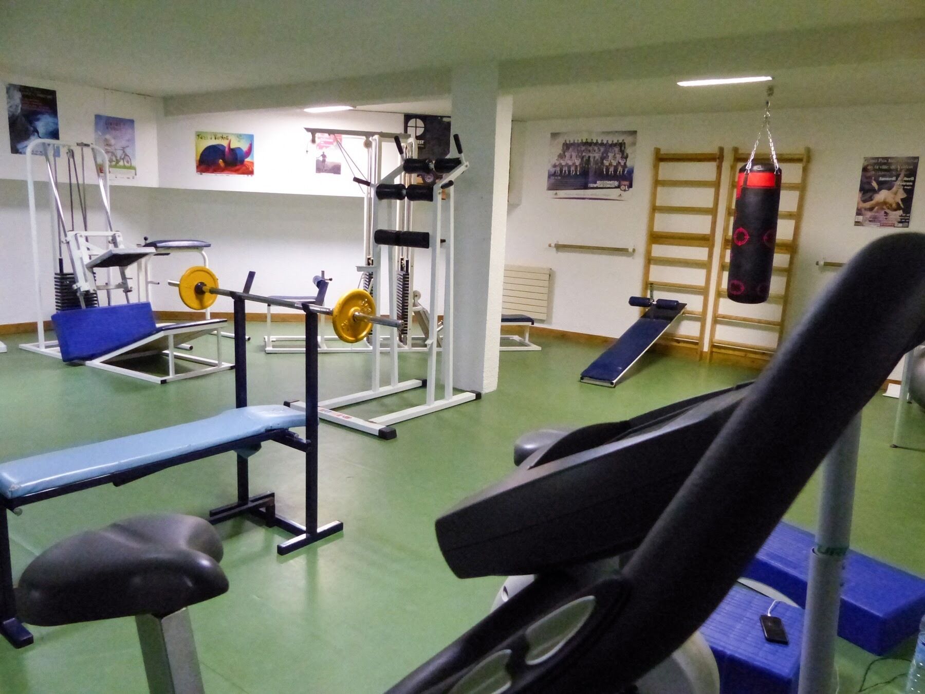 Un gimnasio con diversos equipos de ejercicio, incluyendo una banca, máquina de pesas y saco de boxeo.