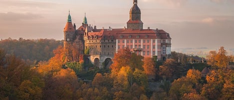 A historic building with multiple towers and a prominent dome, surrounded by autumn foliage.