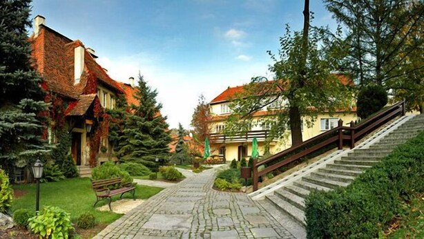 A courtyard with a stone pathway, benches, and a staircase leading to a building with a red-tiled roof. - Hotel Przy Oślej Bramie - Zamek Książ (Walbrzych)