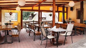 An outdoor cafe with wooden tables and chairs, hanging paper lanterns, and potted plants. - Hotel Przy Oślej Bramie - Zamek Książ (Walbrzych)
