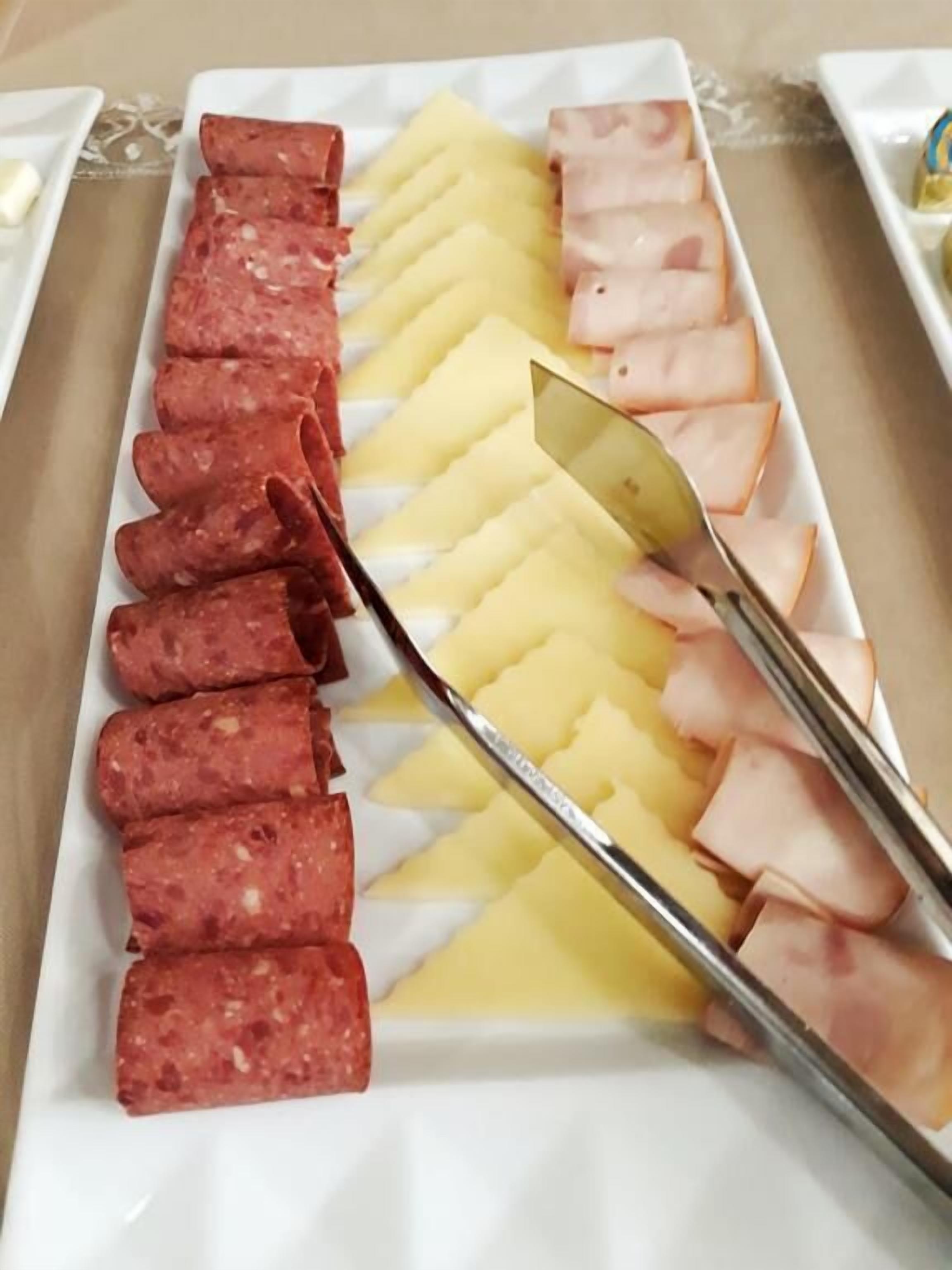 A white rectangular plate with neatly arranged slices of salami and ham.