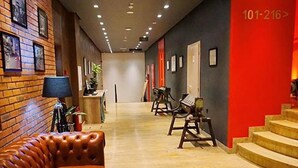 Un hall d’hôtel avec un canapé en cuir, une table basse ronde et un escalier.