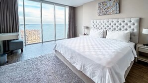 Ein modernes Hotelzimmer mit einem großen Bett, einem Schreibtisch und Meerblick.