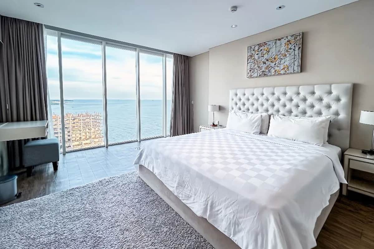 Een moderne hotelkamer met een groot bed, een bureau en uitzicht op zee.