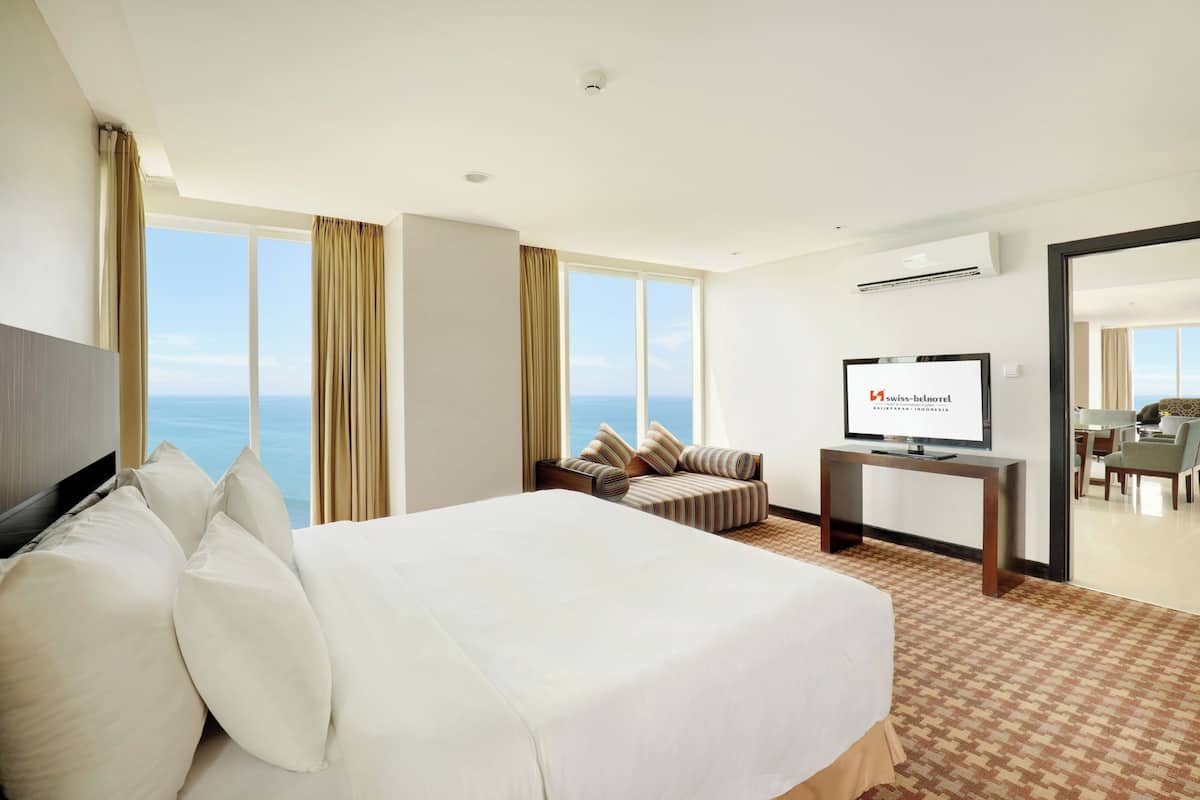 Hotelkamer met een groot bed, een bank, een televisie en uitzicht op de oceaan.