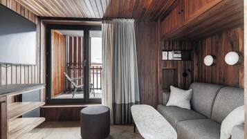 A modern interior with a sofa, a small table, a bench, and a TV.