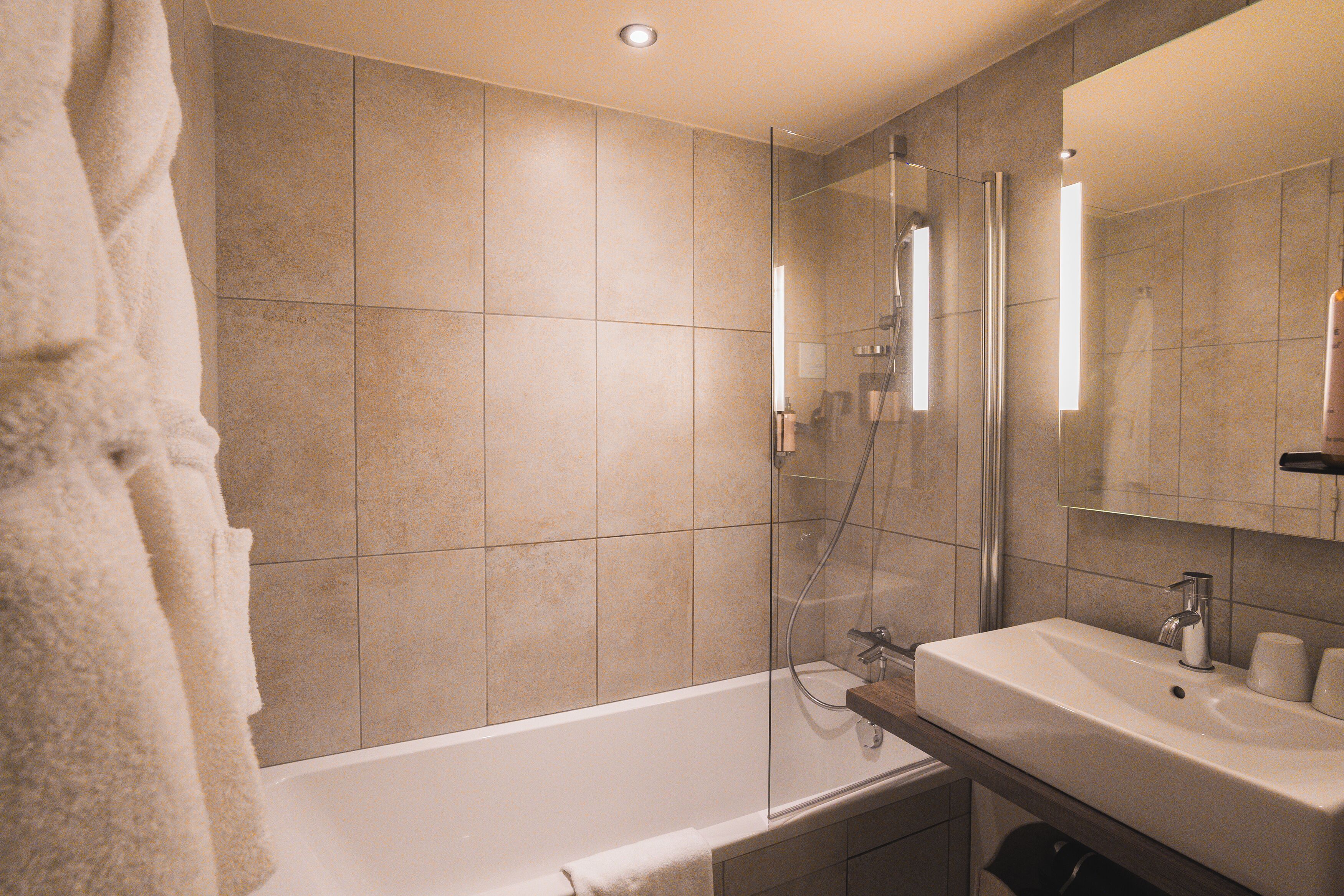 Une salle de bain moderne avec une douche à parois de verre, une baignoire blanche et un meuble-lavabo avec un évier et un miroir.