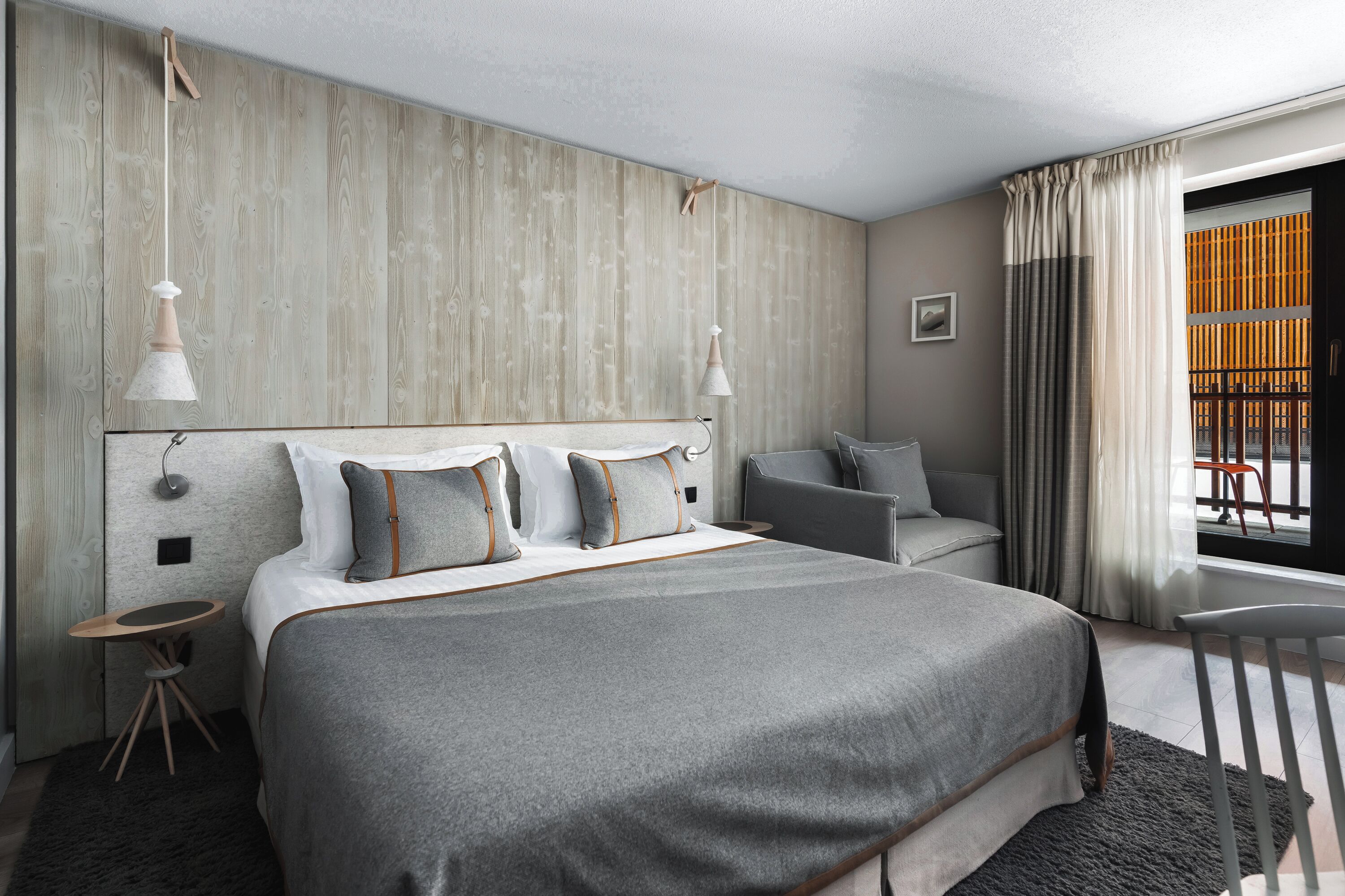 Habitación de hotel moderna con una cama grande, un escritorio pequeño y vistas de la ciudad a través de la ventana.