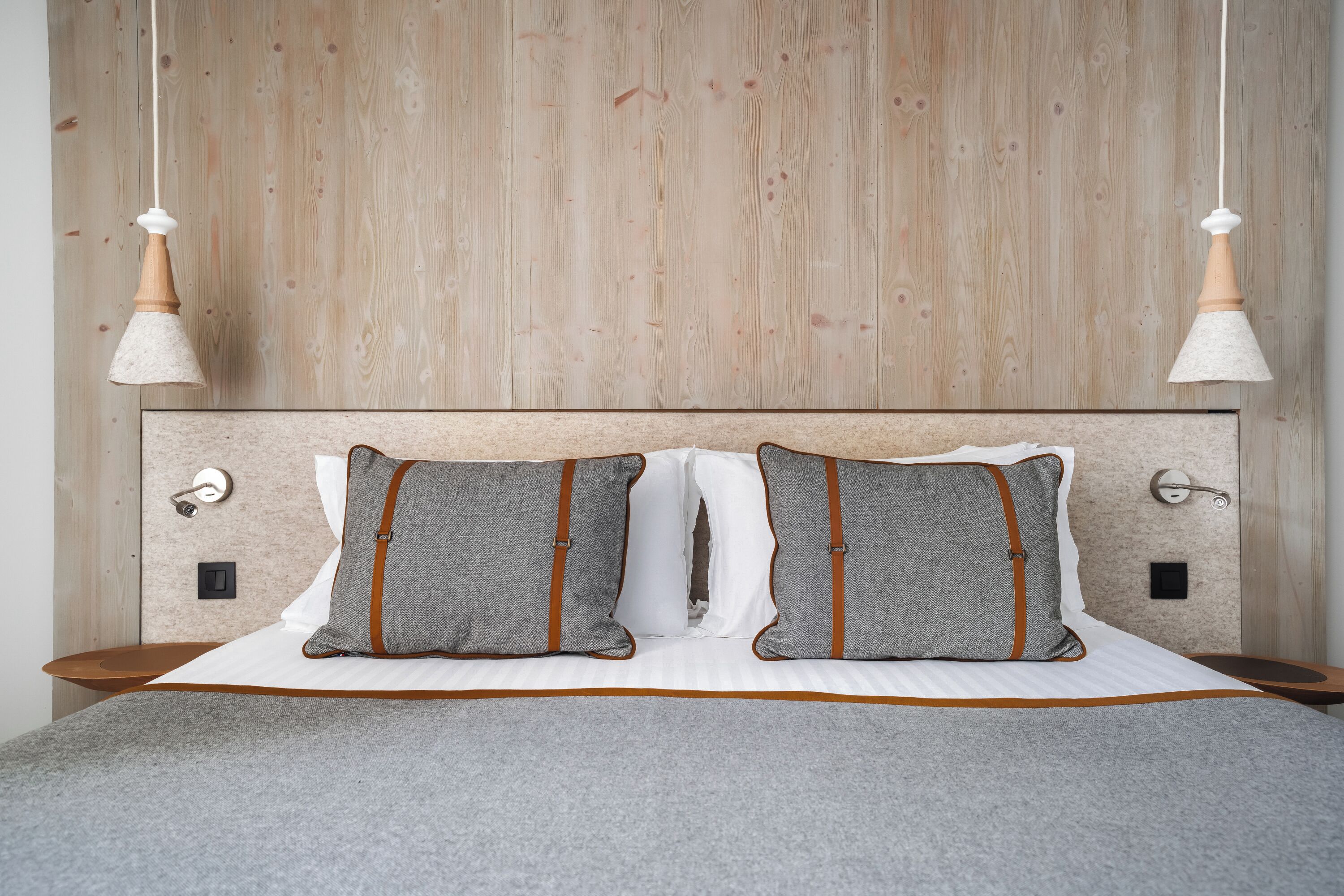 A bed with a wooden headboard, two pillows, and a bedside table.