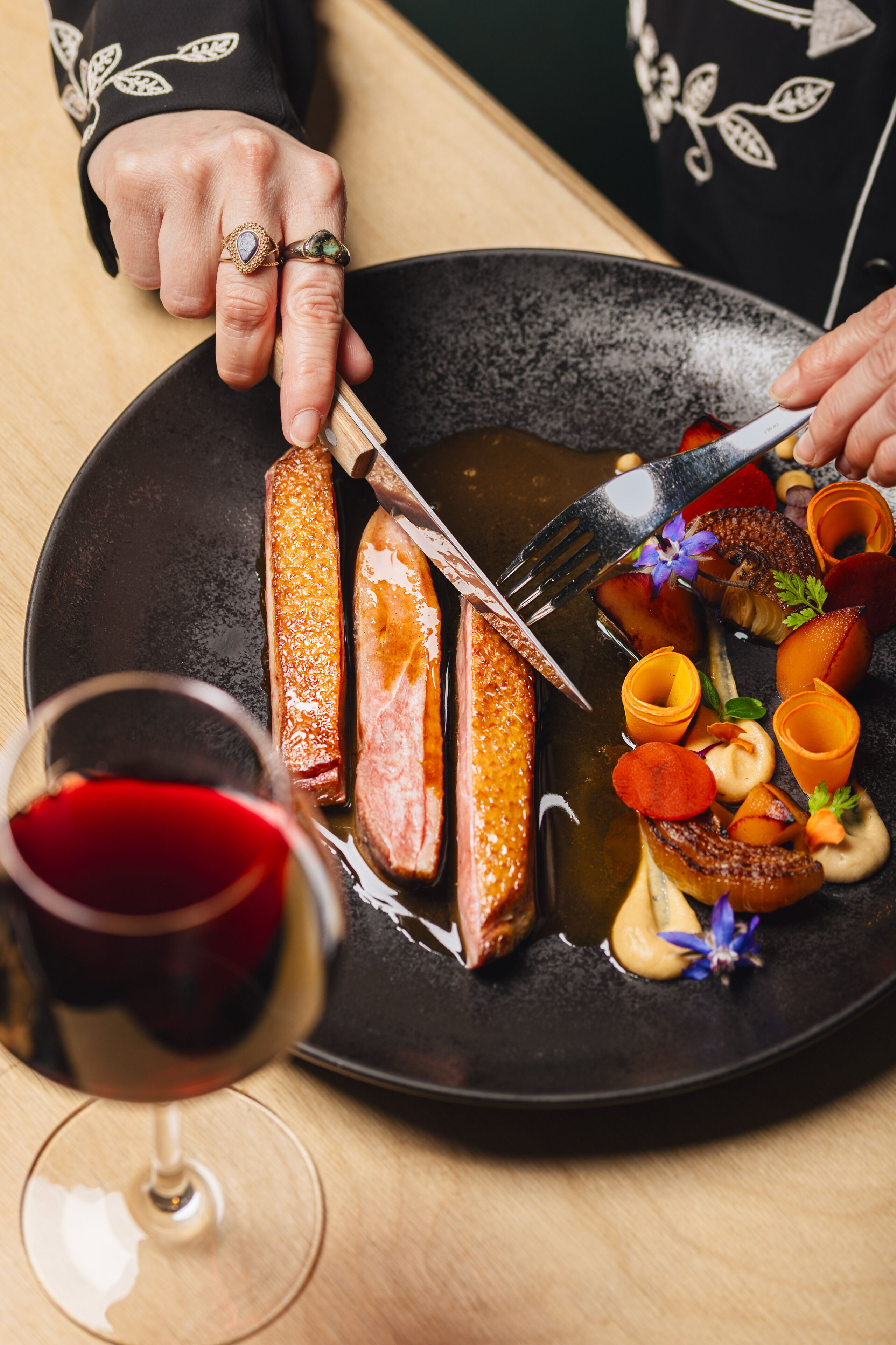 Un plato de comida y una copa de vino tinto.