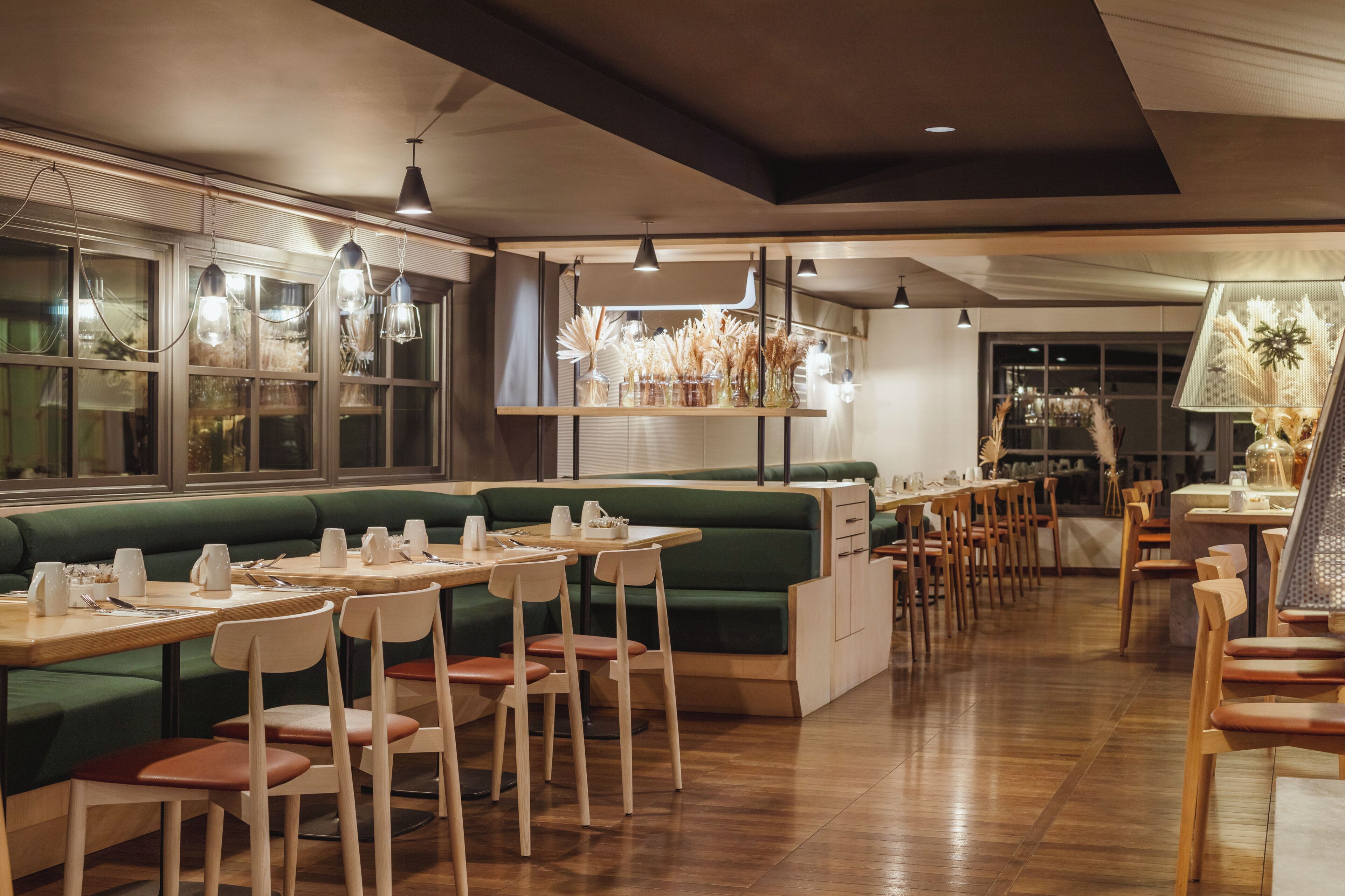 A restaurant with green booths, wooden tables, and chairs.
