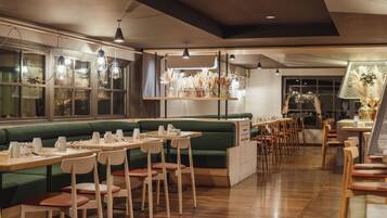 A restaurant with green booths, wooden tables, and chairs.