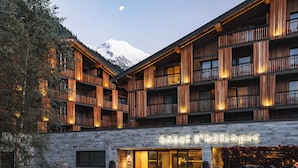 A hotel with a stone facade, wooden balconies, and a mountain view.