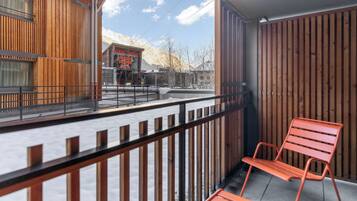 A wooden balcony with metal railings, a wooden wall, and a bench.