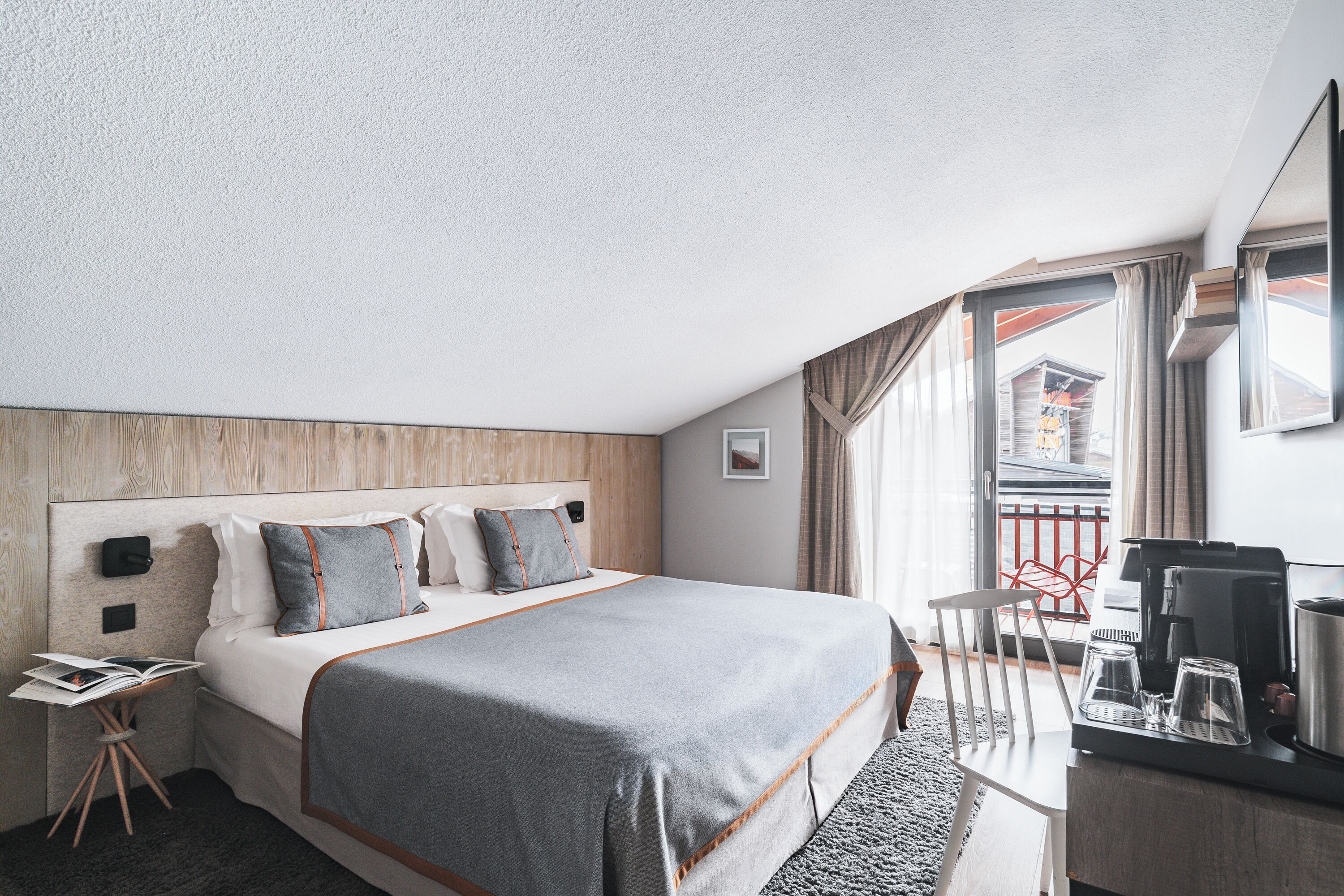 A hotel room with a large bed, a desk with a coffee maker, and a view of the outside.