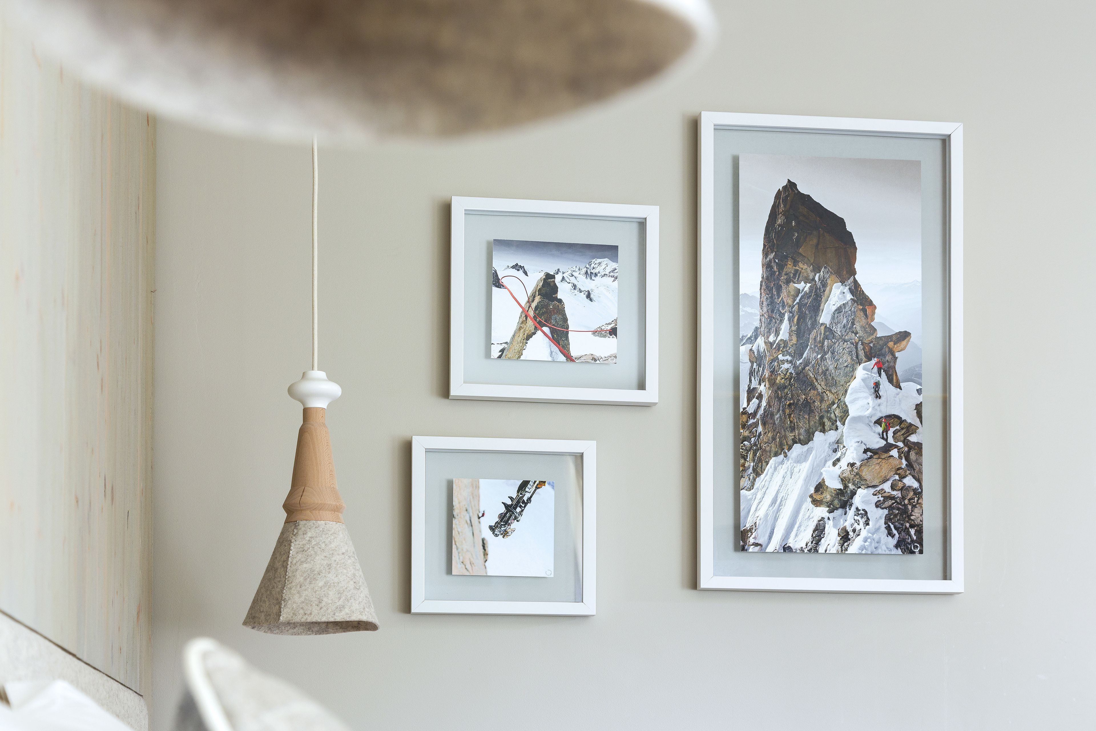 A wall with three framed photographs and a hanging pendant light.