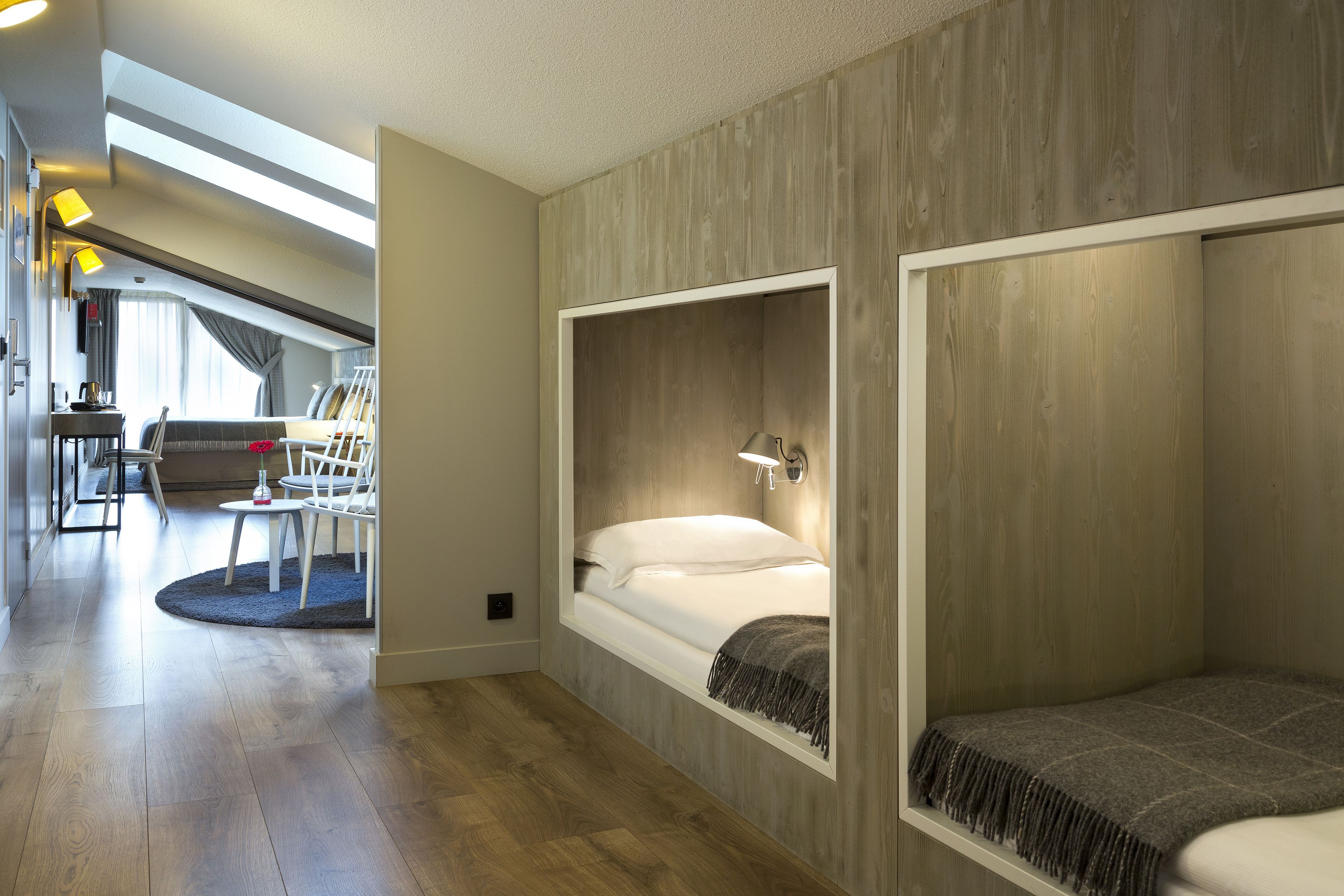 Een moderne hotelkamer met een hoogslaper, een bureau en uitzicht op de stad.