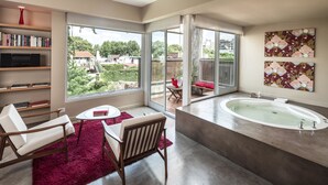 A modern bathroom with a large bathtub, a seating area with a red rug, and a view of the outdoors. - Home Hotel Buenos Aires (Buenos Aires)