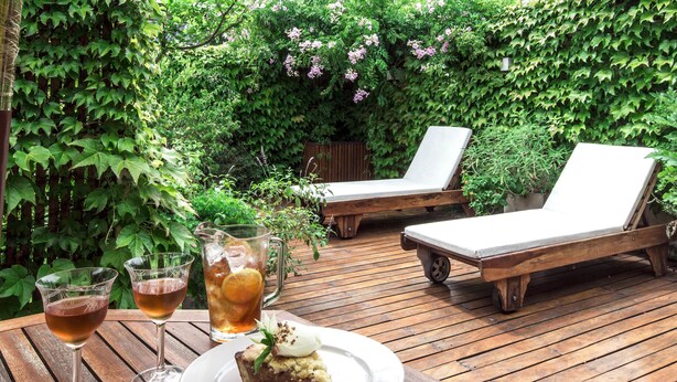 A wooden deck with two lounge chairs and a table with drinks and a dessert. - Home Hotel Buenos Aires (Buenos Aires)