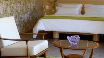 Una habitación de hotel con una cama, una silla, una mesita y una alfombra verde.