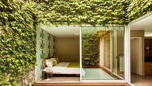 A bedroom with a glass door, a bed, and a view of a room with a radiator. - Home Hotel Buenos Aires (Buenos Aires)